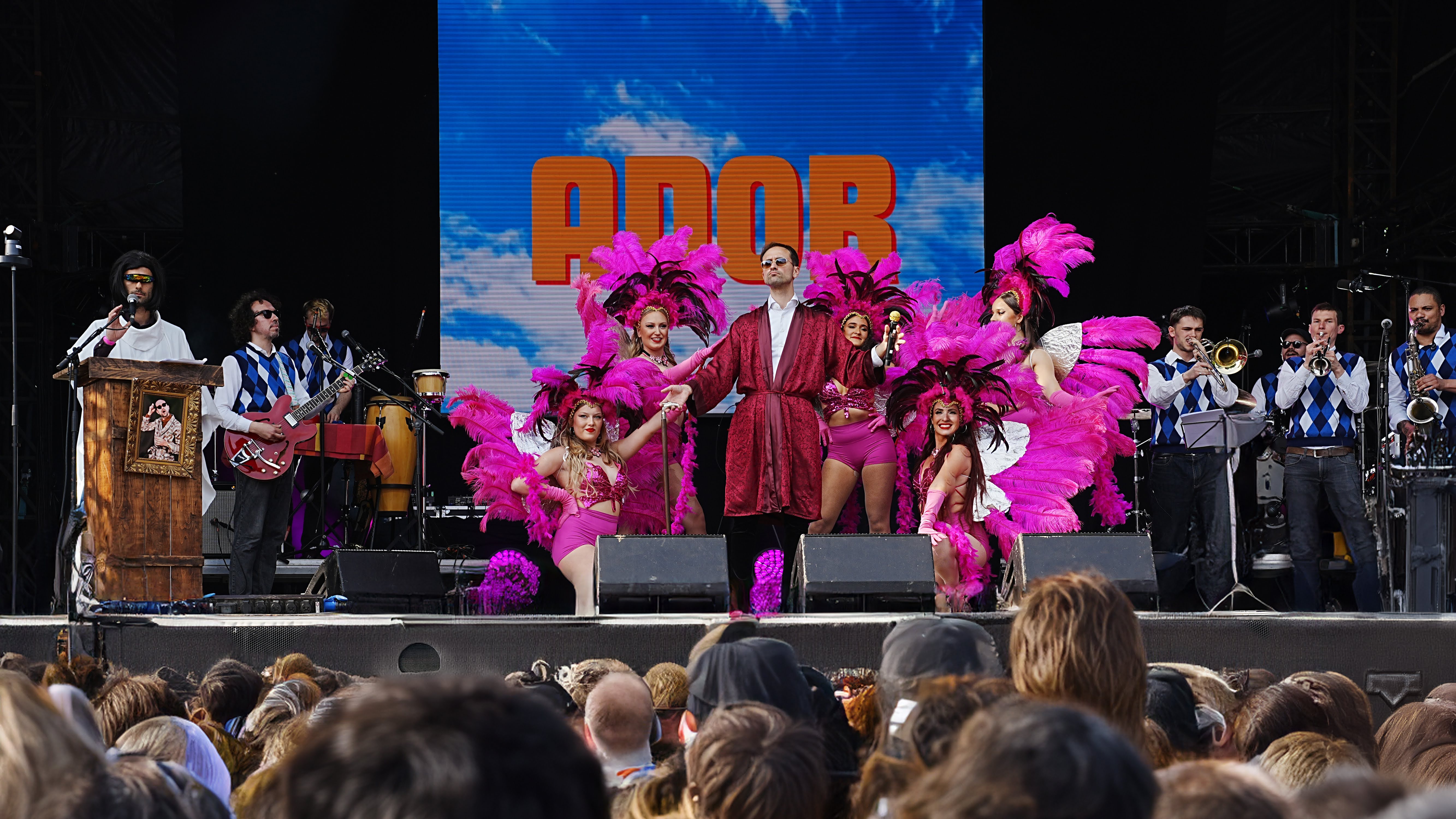 Performance live de l'opéra rock décalé d'Ador avec des musiciens et des danseuses en costumes de cabarets sur la scène du CCM festival